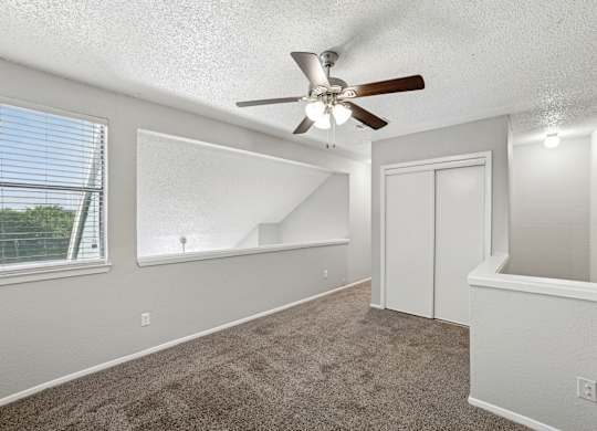 A room with a ceiling fan and carpeted floor.