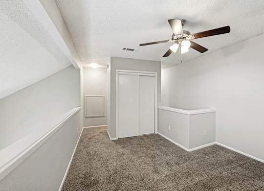 A room with a ceiling fan and carpeted floor.