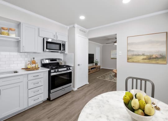 a kitchen with white cabinets and a white marble table with a bowl of fruit on it  at Sunset Heights, San Antonio, TX, 78209