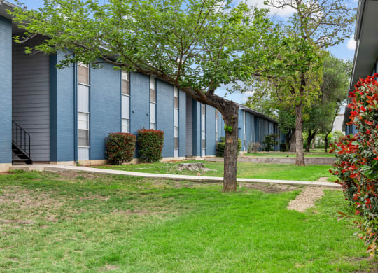a building with blue siding and a tree in front of it  at Sunset Heights, San Antonio, TX