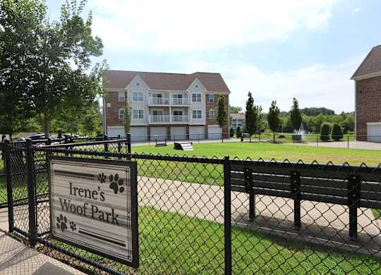 A sign that says Irene's Woof Park is in front of a black fence.