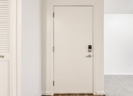 A white door with a black handle and a lock at Huntington Cove Apartments, Merrillville, IN, 46410