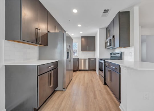a large kitchen with stainless steel appliances and white counter tops at The Vinings Apartments, Richmond, Virginia
