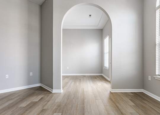 A room with a large arched doorway and wooden flooring.
