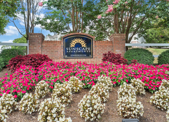 a sign and flowers in front of a brick wall at Sunscape Apartments, Roanoke, VA