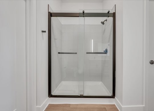 a shower with a glass door in a white bathroom