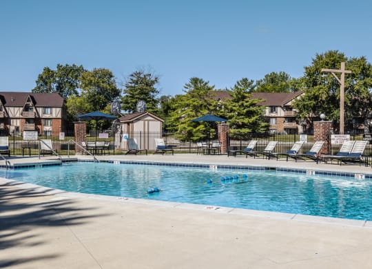 a swimming pool with chairs and umbrellas in front of apartment buildings East Indianapolis
