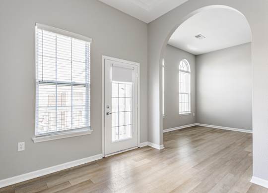 A room with a white door, a window with blinds, and a wall socket.