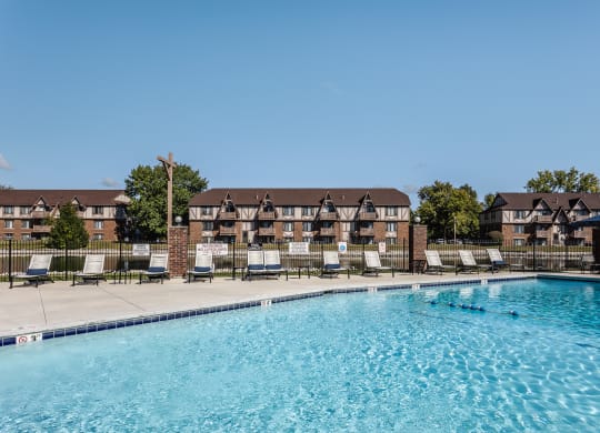 an outdoor pool with lounge chairs and an apartment building in the background Indy