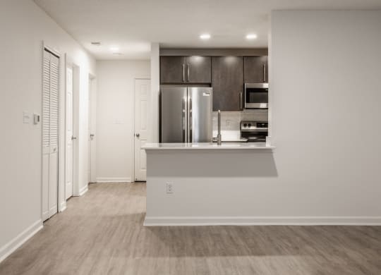a living room with a kitchen and a door to a hallway at Latitudes Apartments, Indianapolis, IN