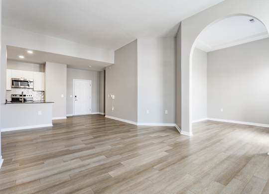 A spacious room with wooden flooring and a large archway.