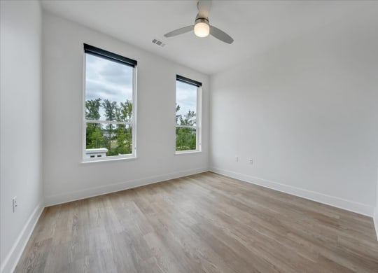 an empty room with three windows and a ceiling fan at Luxe 360 on Centerpointe Apartments, Midlothian, Virginia