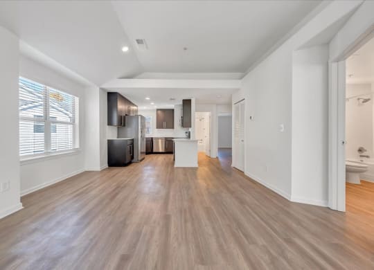 a living room with a kitchen and a large window at The Vinings Apartments in Richmond, VA 