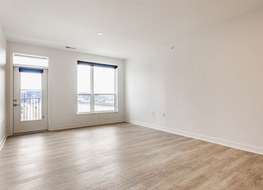 A large empty room with wooden floors and two windows at Upper Vue Flats, Dublin