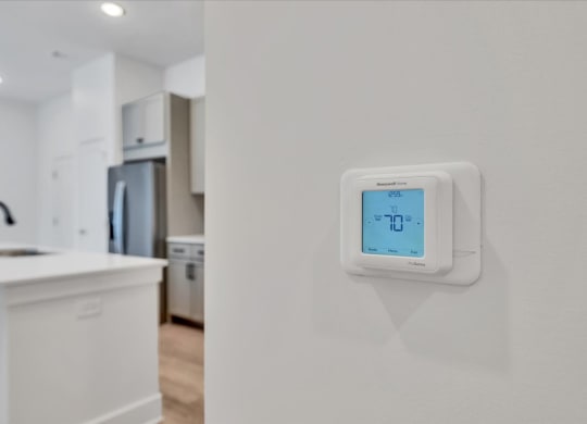 a white kitchen with an electric thermostat on the wall