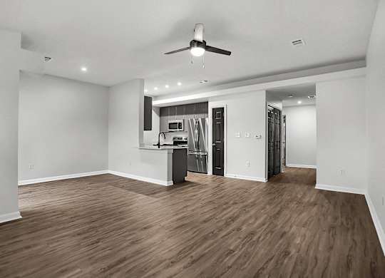 an empty living room with a kitchen and a ceiling fan at Latitudes Apartments, Indiana, 46237