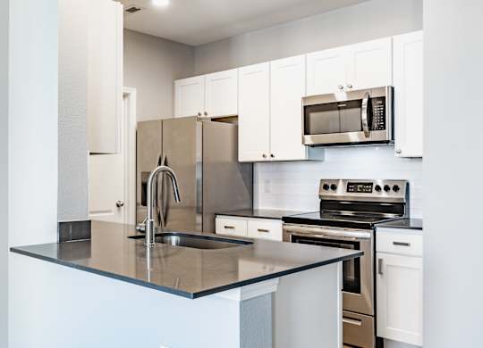 A kitchen with a sink, stove, and refrigerator.