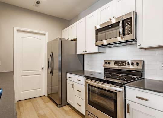 A kitchen with a stove, oven, refrigerator, and microwave.