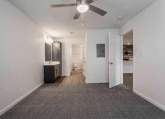 an empty living room with a ceiling fan and a kitchen at Latitudes Apartments, Indianapolis, 46237