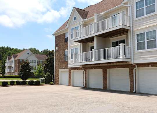 A large two-story house with a balcony and garage doors.
