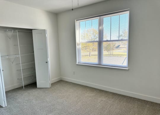 a bedroom with a large window and a closet  at Signature Pointe Apartment Homes, Athens, AL