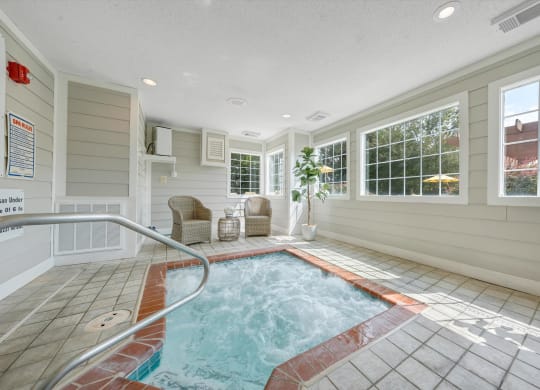 a hot tub in a room with a large window at Sunscape Apartments, Virginia