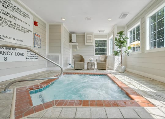 a hot tub with two chairs and a plant at Sunscape Apartments, Virginia