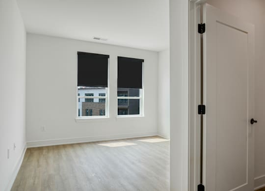 A room with a white door and a window with a view of a building outside.