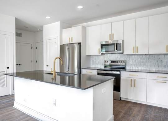 A kitchen with white cabinets and a black countertop.