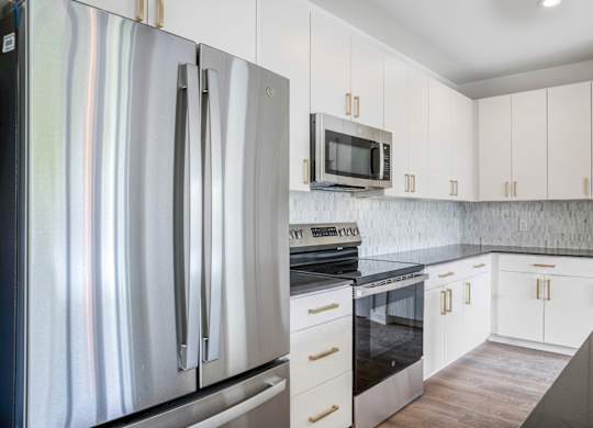 A modern kitchen with a stainless steel refrigerator and white cabinets.