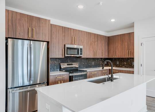 A modern kitchen with a white countertop and wooden cabinets.