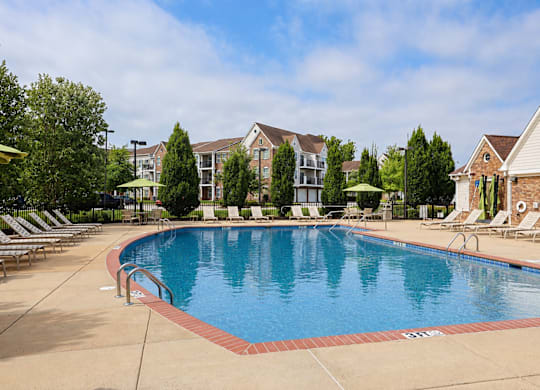 A large swimming pool surrounded by lounge chairs and trees.