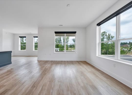 an empty living room with large windows and hardwood floors at Luxe 360 in Midlothian, Virginia, 23114