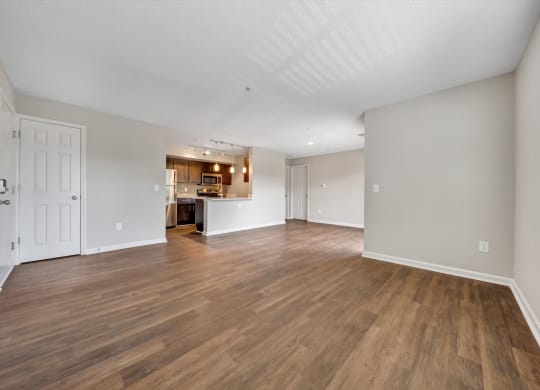a spacious living room with hardwood floors and a kitchen in the background at Sunscape Apartments, Virginia, 24018