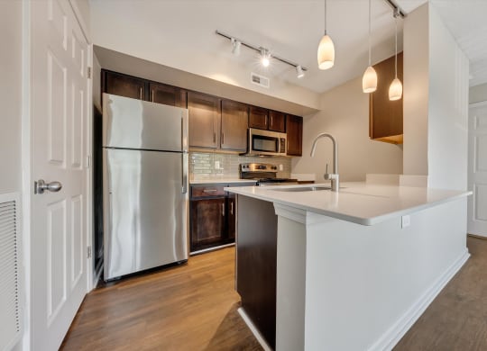 a kitchen with white countertops and dark wood cabinets at Sunscape Apartments, Virginia, 24018