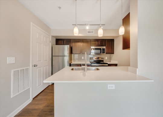 a kitchen with white countertops and wooden cabinets at Sunscape Apartments, Virginia, 24018