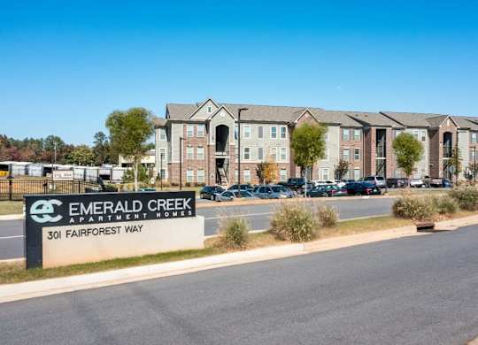 A sign for Emerald Creek Apartment Homes stands in front of a building.