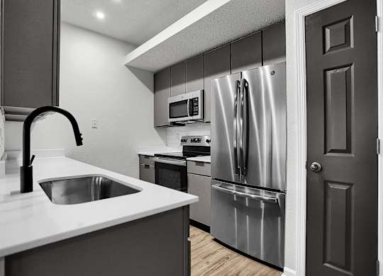 a kitchen with stainless steel appliances and a white counter top at Latitudes Apartments, Indianapolis