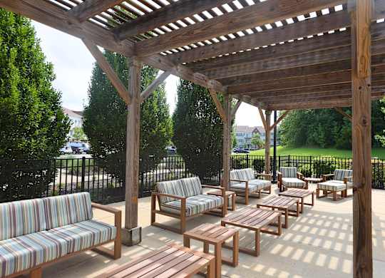 A wooden pergola with striped couches and tables.