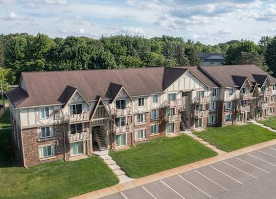 A large apartment complex with a parking lot in front.