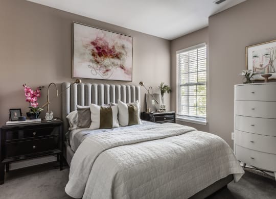 a bedroom with a bed and a dresser at Alexandria of Carmel Apartments, Carmel, Indiana