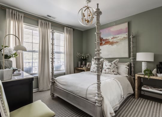 a bedroom with a white bed and a painting on the wall at Alexandria of Carmel Apartments, Carmel, IN, 46032