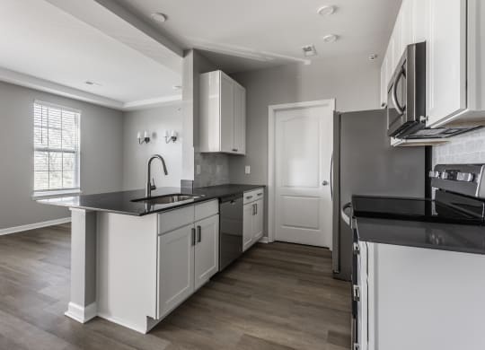 an empty kitchen with white cabinets and black counter tops  at Alexandria of Carmel Apartments, Carmel, IN, 46032