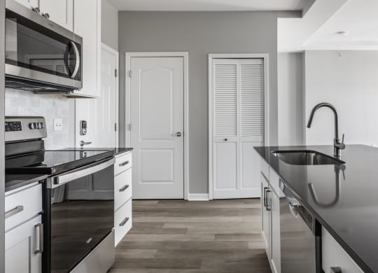 a kitchen with black counter tops and white cabinets and a sink at Alexandria of Carmel Apartments, Carmel