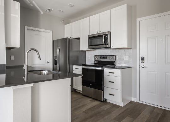 a kitchen with white cabinets and stainless steel appliances at Alexandria of Carmel Apartments, Indiana