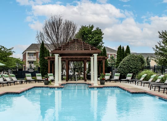 a swimming pool with a gazebo and chairs around it at Alexandria of Carmel Apartments, Indiana