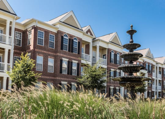 a large brick building with a fountain in front of it at Alexandria of Carmel Apartments, Carmel, Indiana