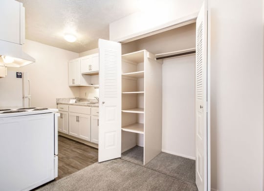 a renovated kitchen with white appliances and a closet with shelves at Apple Ridge Apartments, Walker, MI, 49534