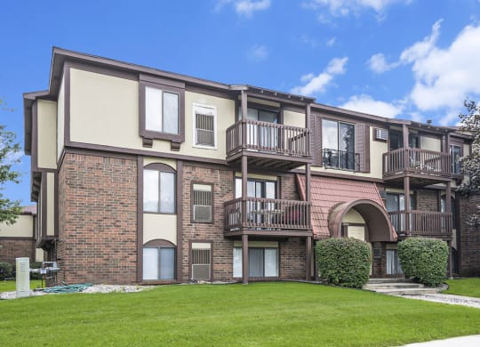 a brick apartment building with balconies and a green lawn at Apple Ridge Apartments, Michigan, 49534