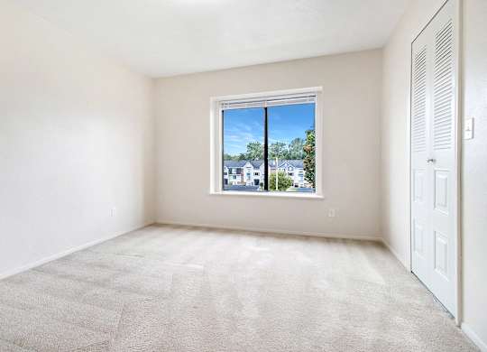 A bedroom with a carpeted floor and a window at Arbor Lakes Apartments in Elkhart, IN